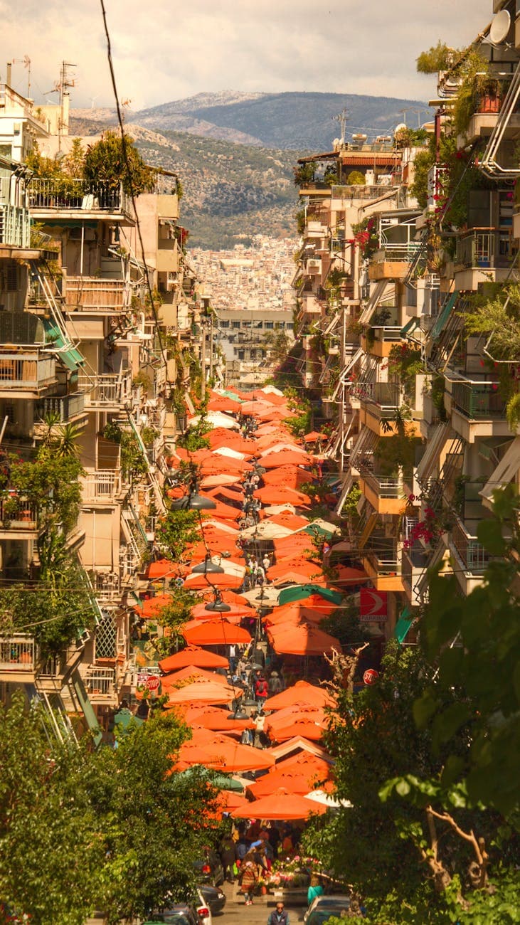 Aerial view of a bustling street market in Athens, Greece, with vibrant red umbrellas, showing retail opportunity in the Greek market