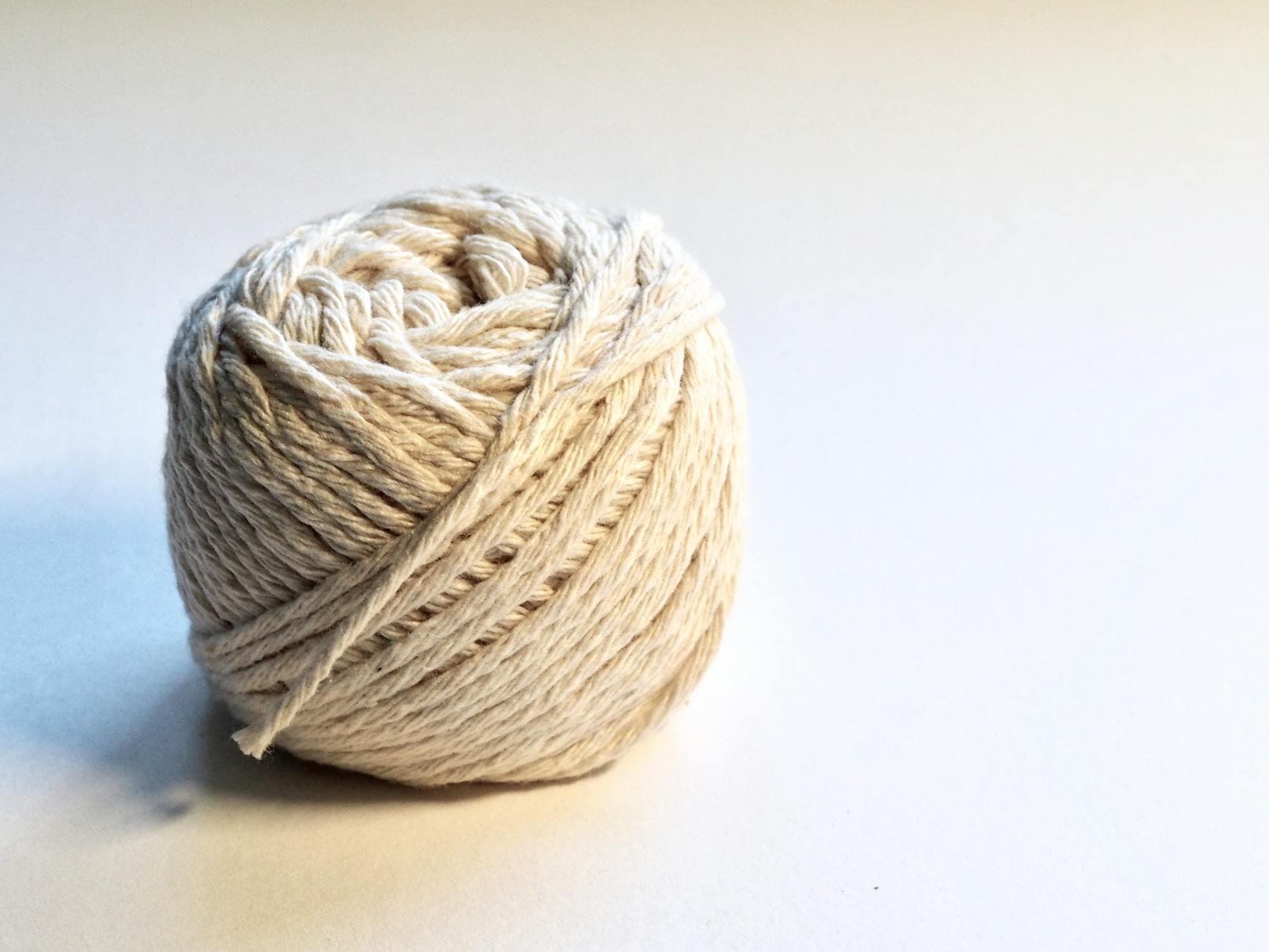 Close-up of natural cotton yarn ball on a white background, representing the thread used in tea bags