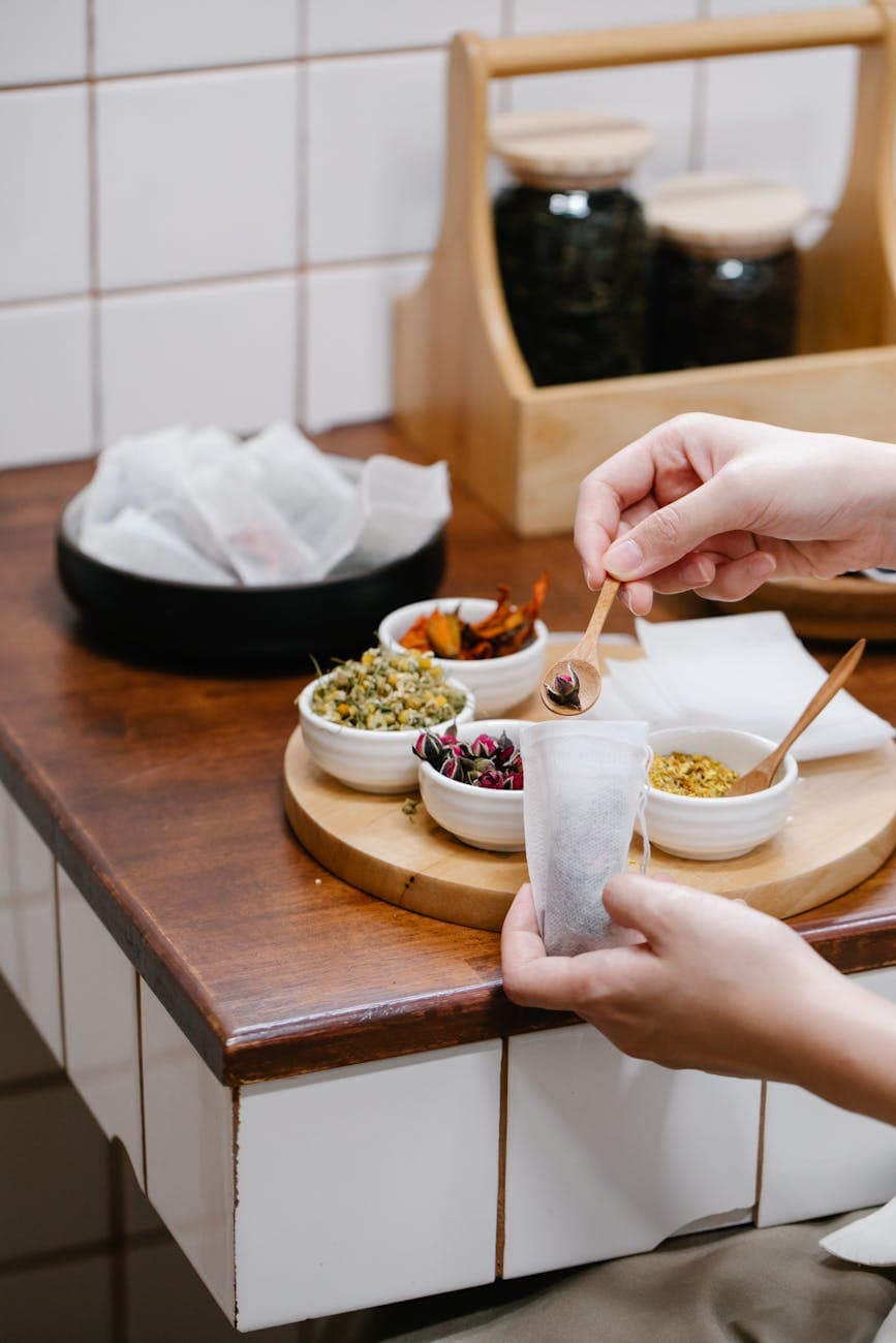 Hands preparing herbal tea with assorted dried herbs in a cozy kitchen