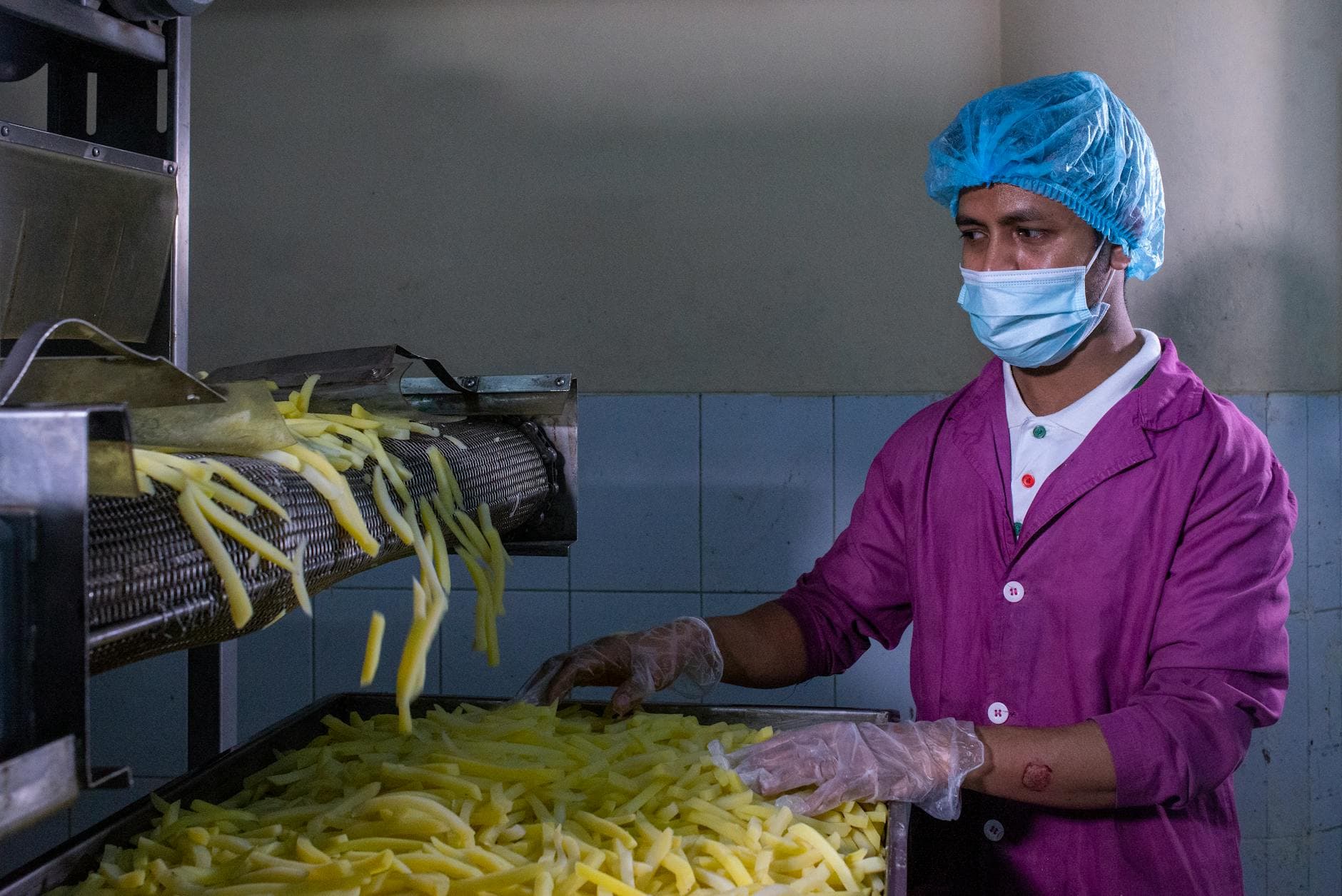 Factory worker in protective gear monitoring food production quality control process