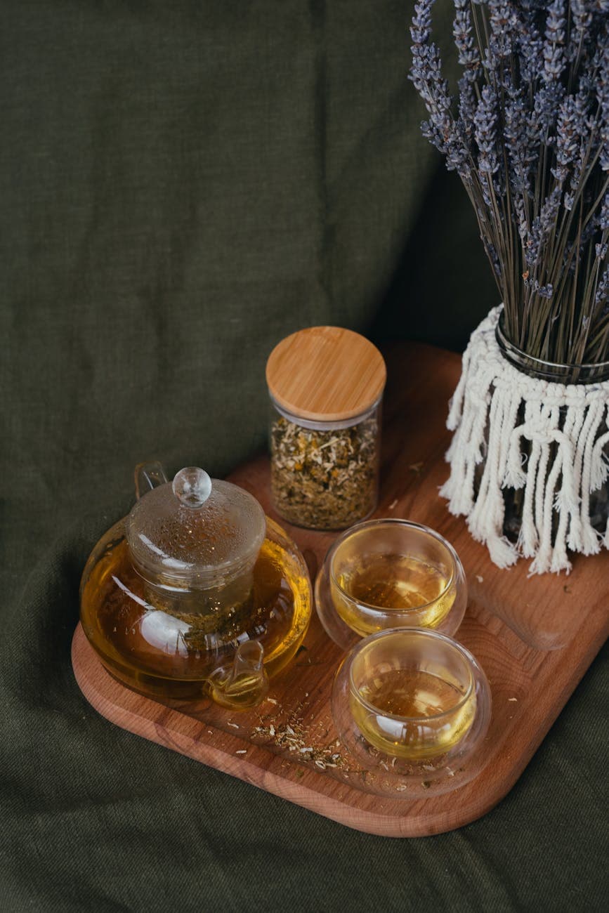 Clear teapot with mountain tea steeping on a wooden board showing the golden-amber infusion colour