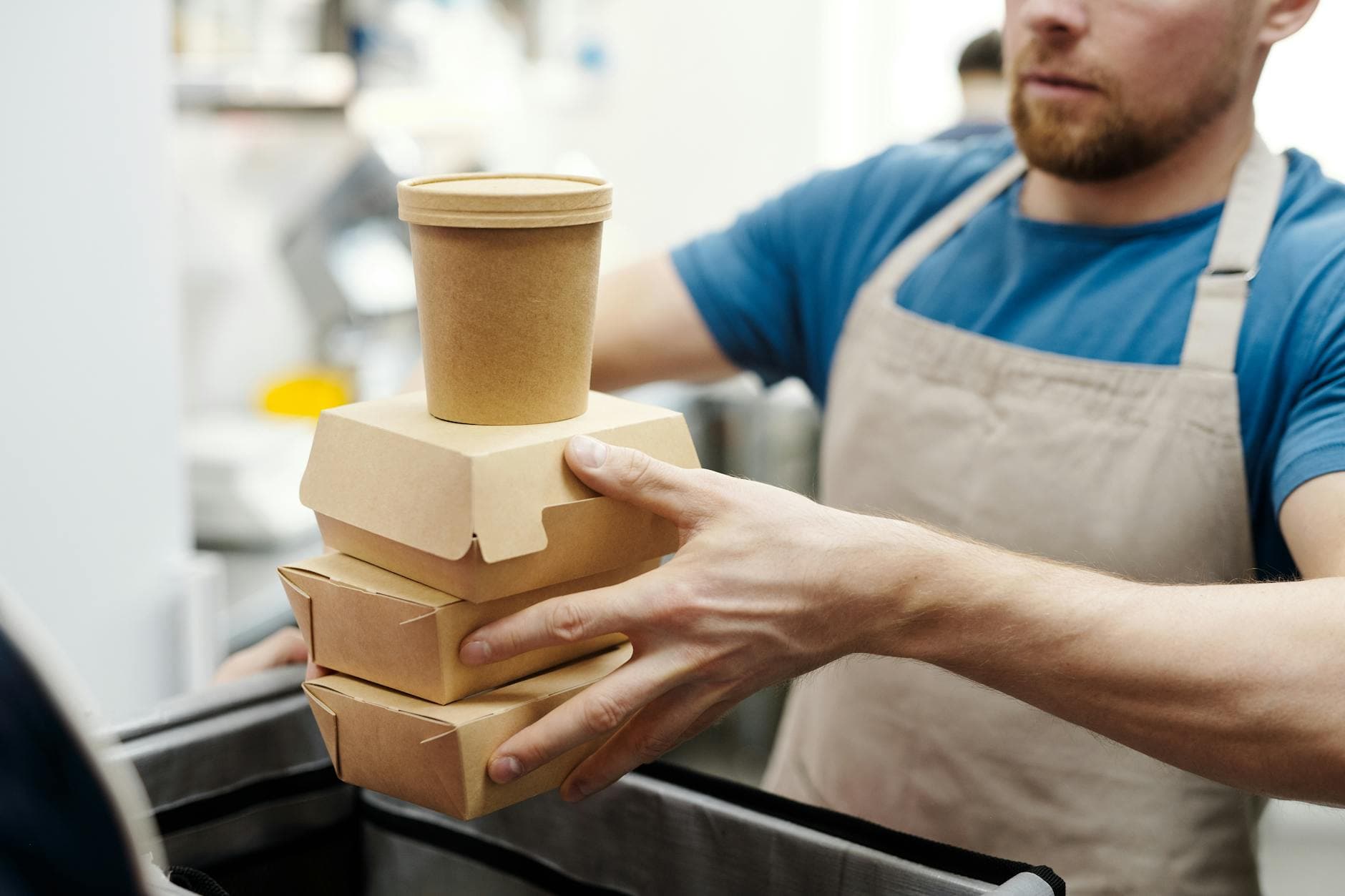 Man stacking eco-friendly food containers in a kitchen setting
