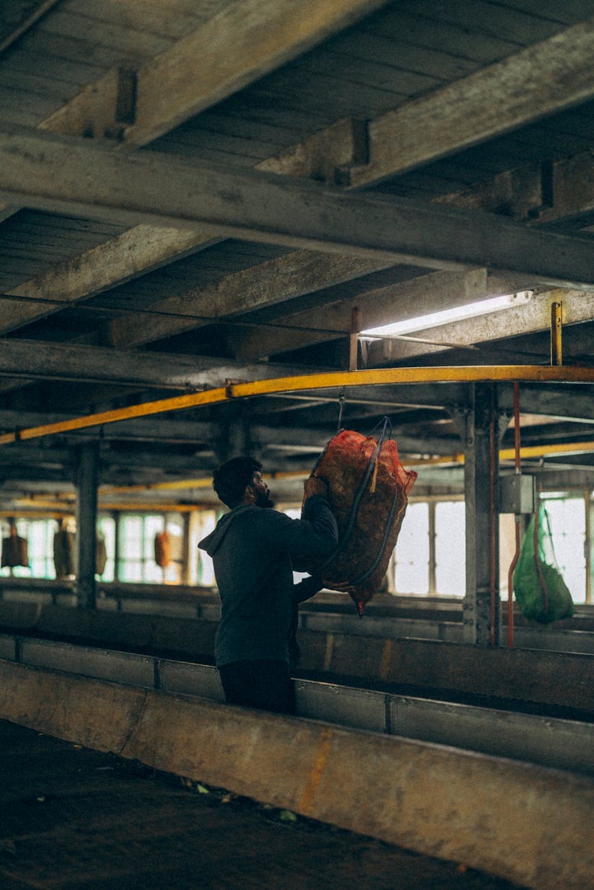 Worker lifting a heavy sack inside a tea factory, showing the physical scale of bulk tea bag production