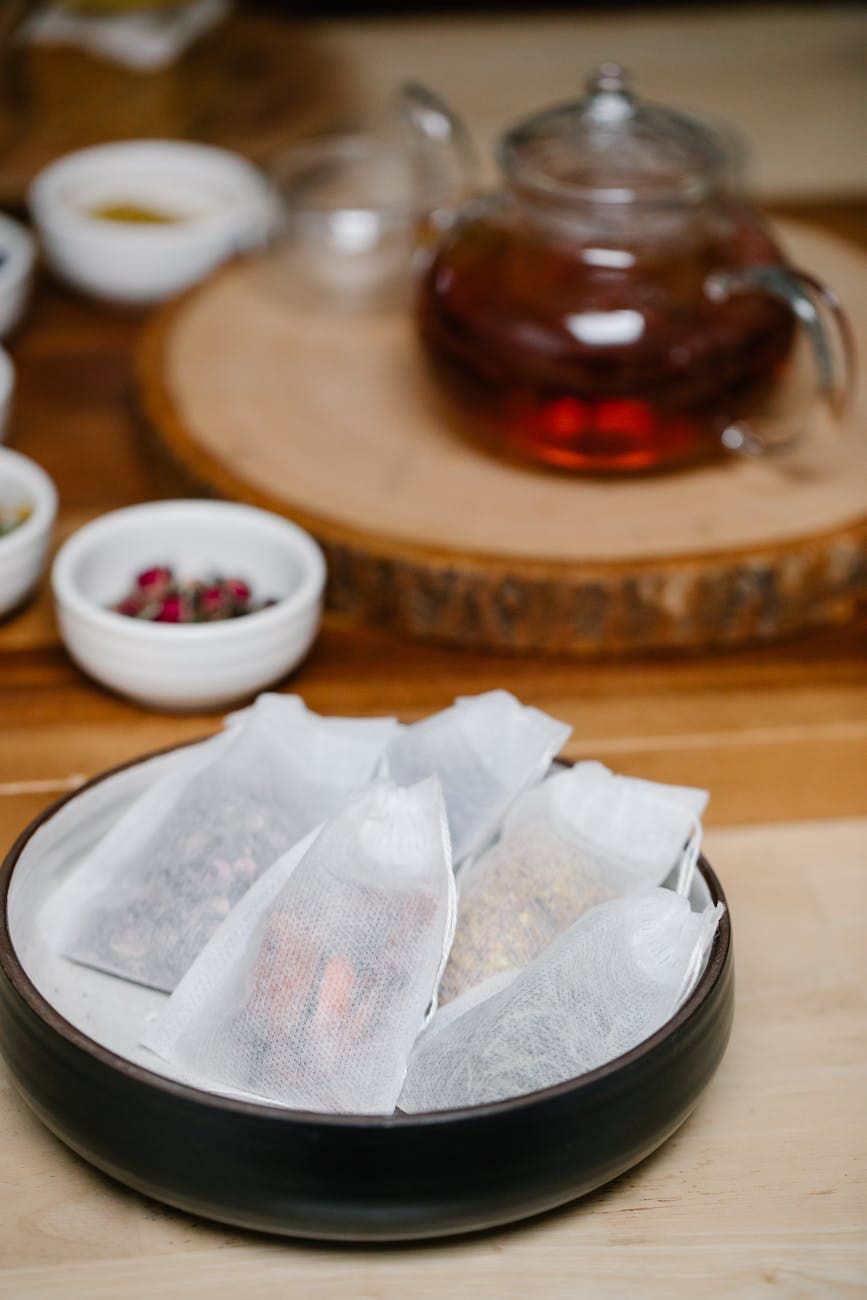 Herbal tea bags in a bowl with loose herbs nearby, illustrating the variety of ingredients available for co-packing
