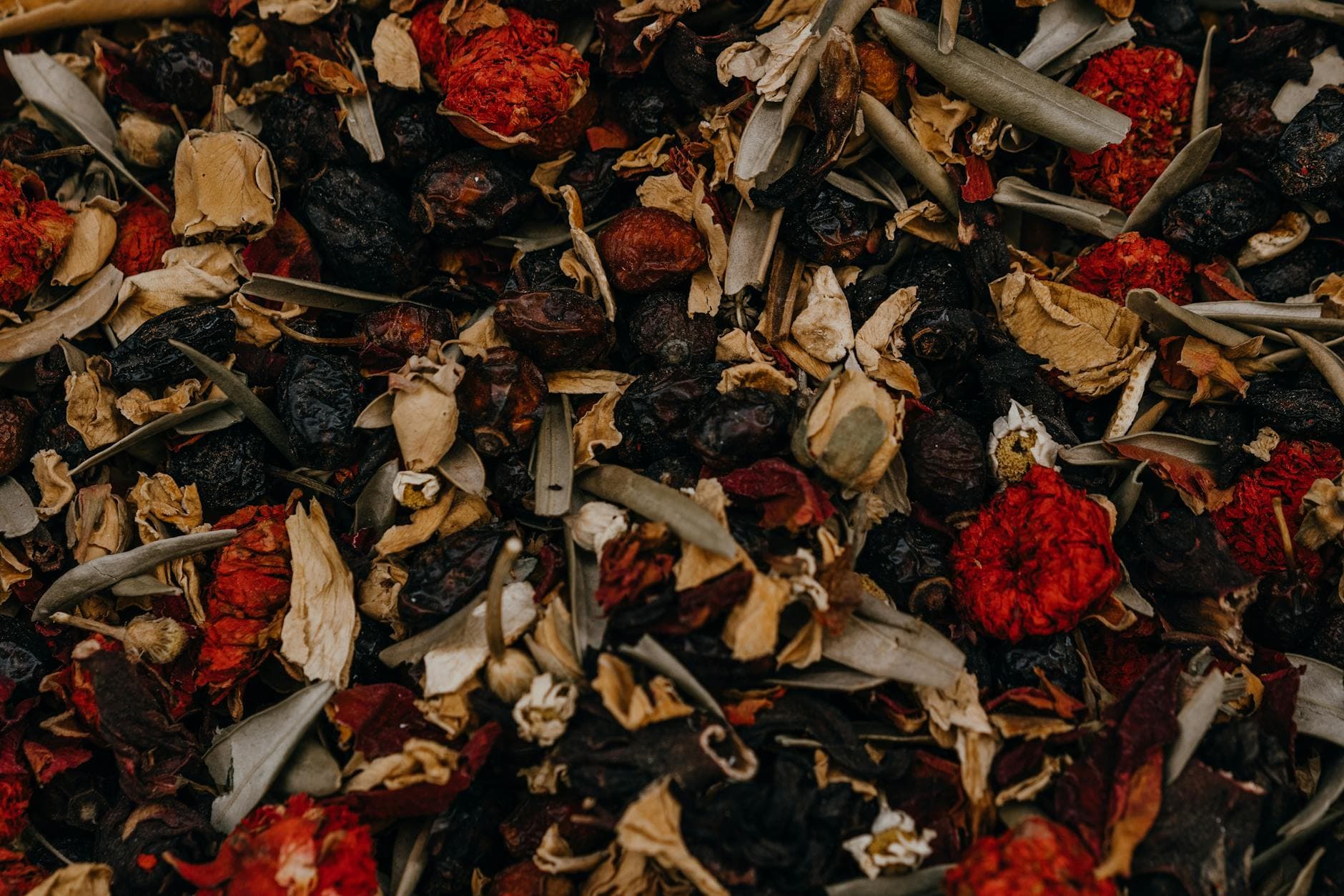 Close-up of a double-chamber tea bag being prepared with herbal ingredients in ceramic bowls, illustrating the filling process for herbal blend bags