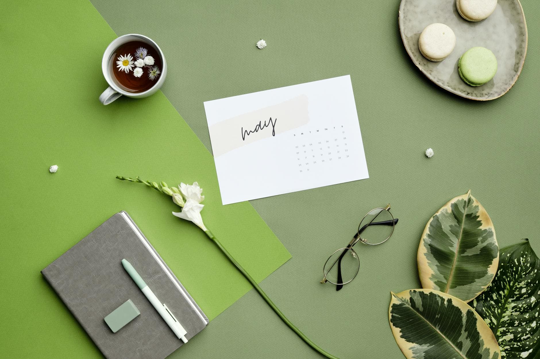 Calendar and journal on a green desk with a cup of tea, representing production planning and scheduling