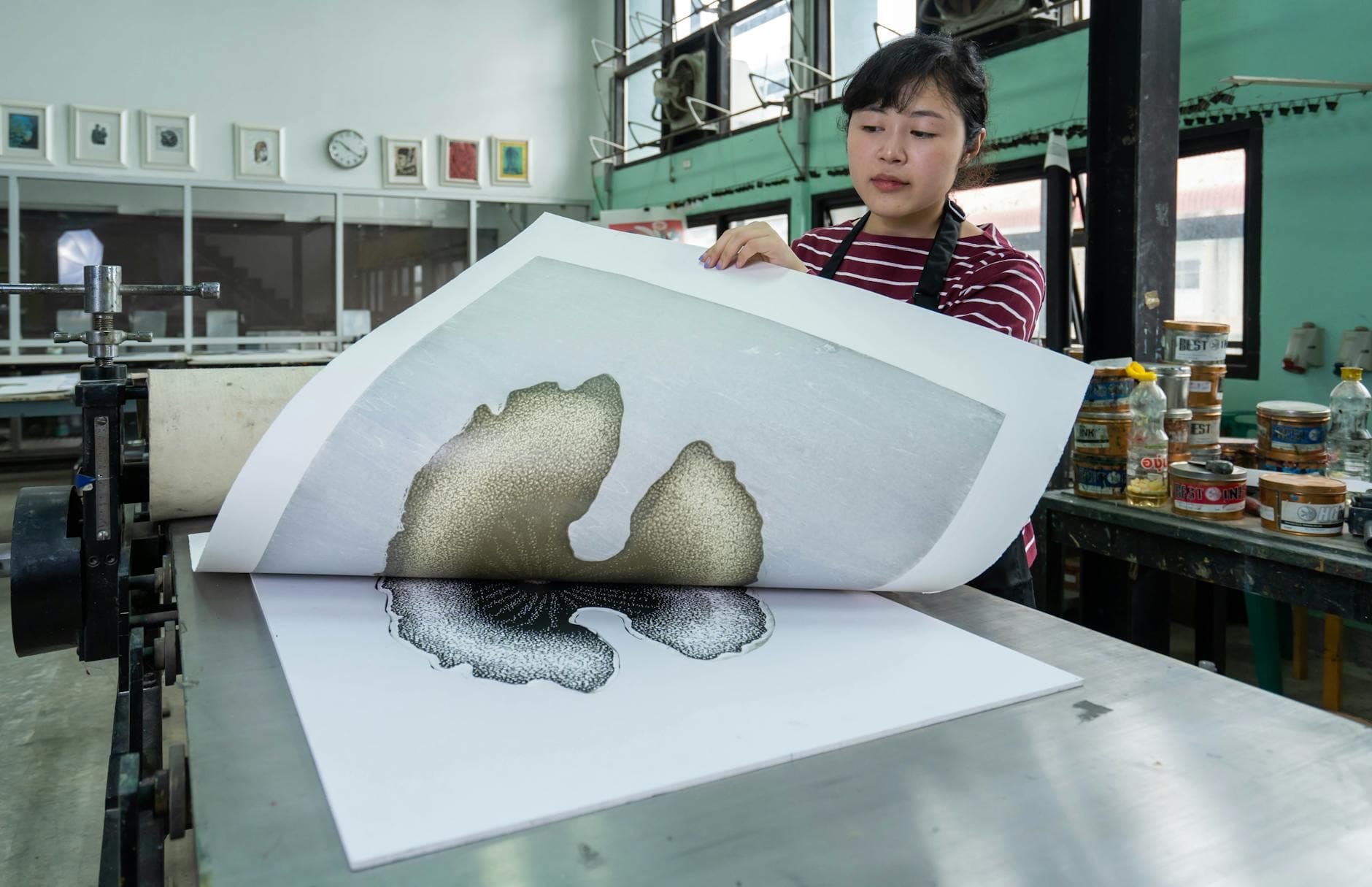 Woman inspecting a freshly printed packaging design in a modern printmaking studio