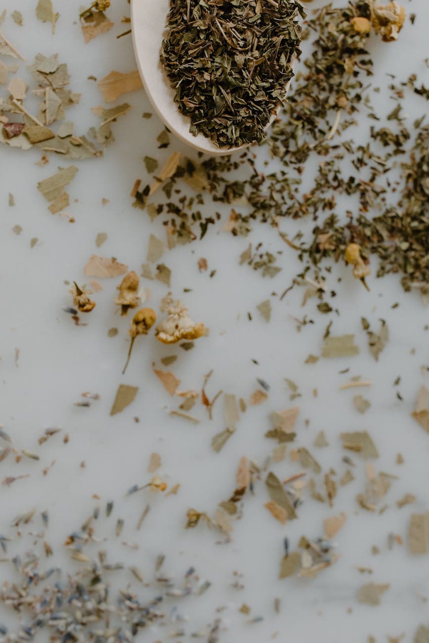 Dried mint, chamomile, and lavender scattered on a marble surface, evoking the family herb business since 1990
