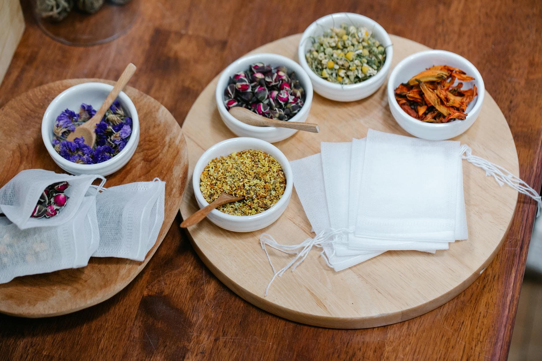 Wooden bowls of loose tea variety - black, green, herbal, and fruit infusions side by side.